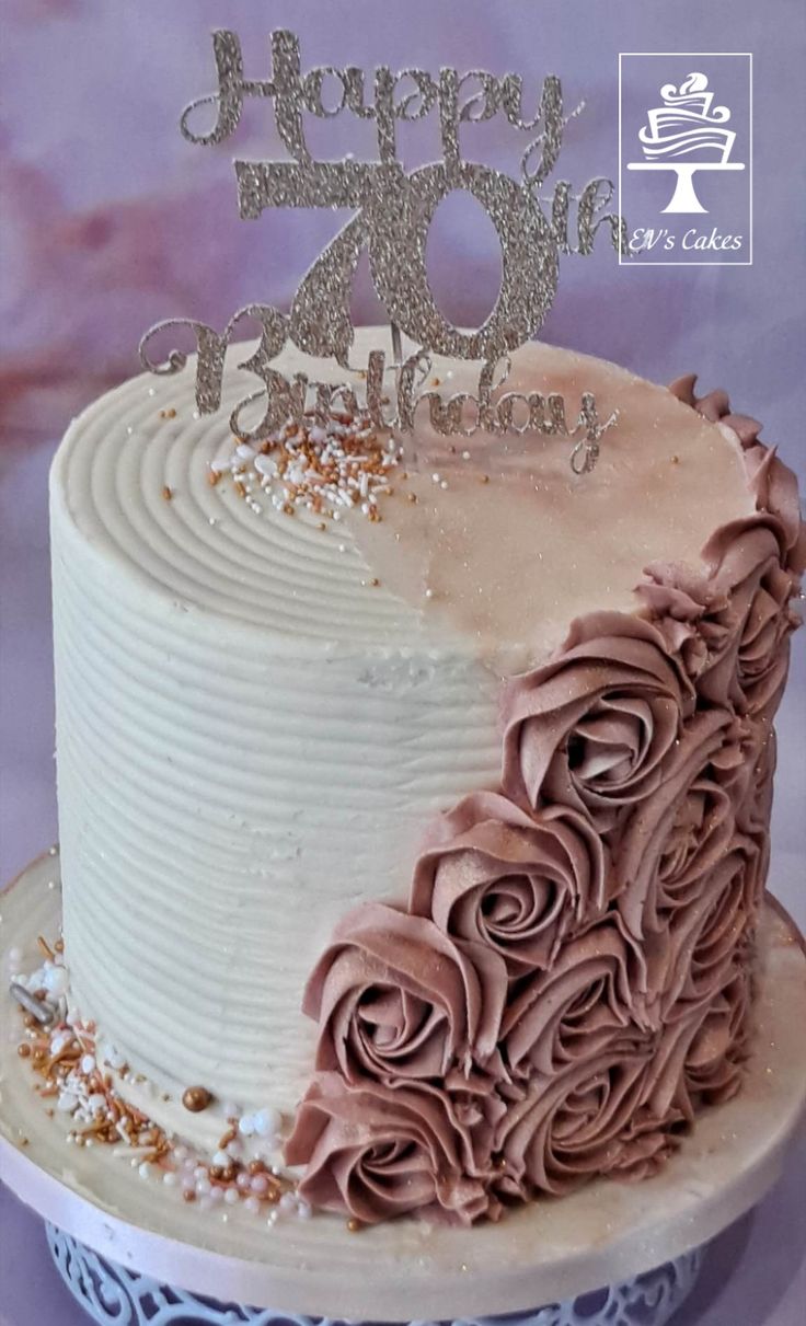 a white cake with pink frosting and rosettes on the top that says happy 70th birthday