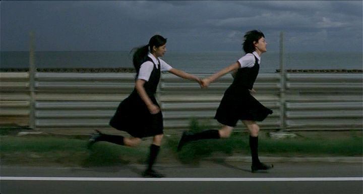 two women in black and white dresses holding hands while running down the street with dark clouds behind them