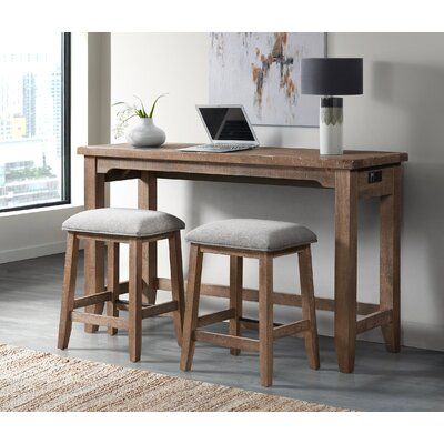 a wooden desk with two stools and a laptop on top of it in front of a window