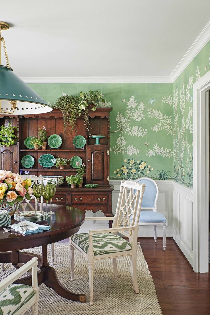 a dining room with green walls and floral wallpaper