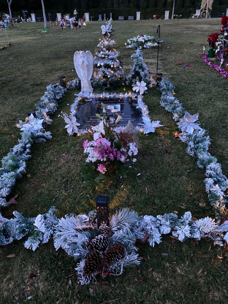 an outdoor cemetery decorated with flowers and pineconis in the evening light, surrounded by candles and wreaths