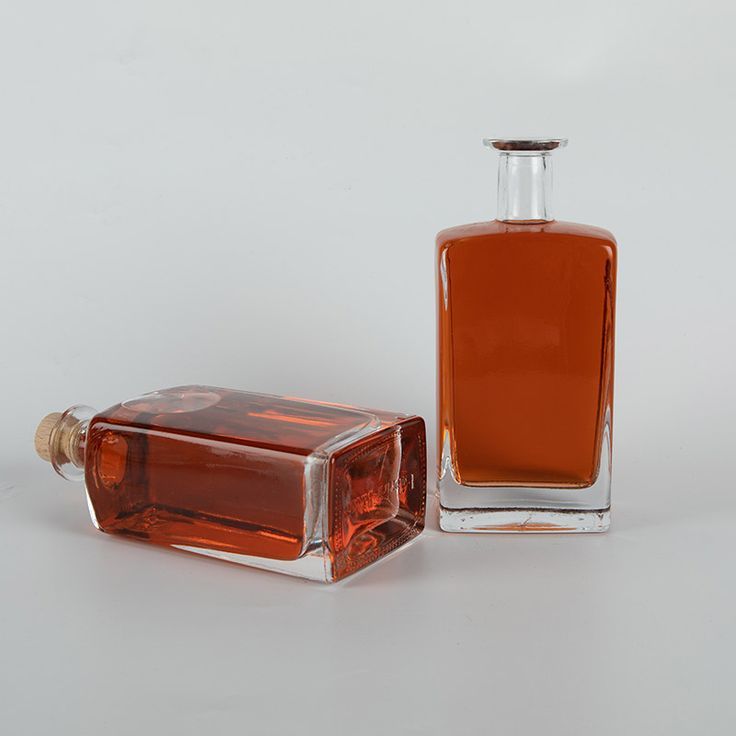 an empty glass bottle sitting next to a small square container