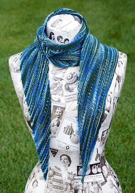 a mannequin with blue beads on it's neck in front of green grass