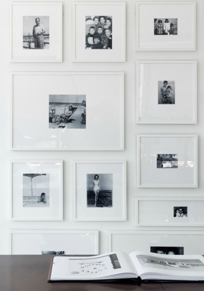 an open book sitting on top of a wooden table next to a wall covered in pictures