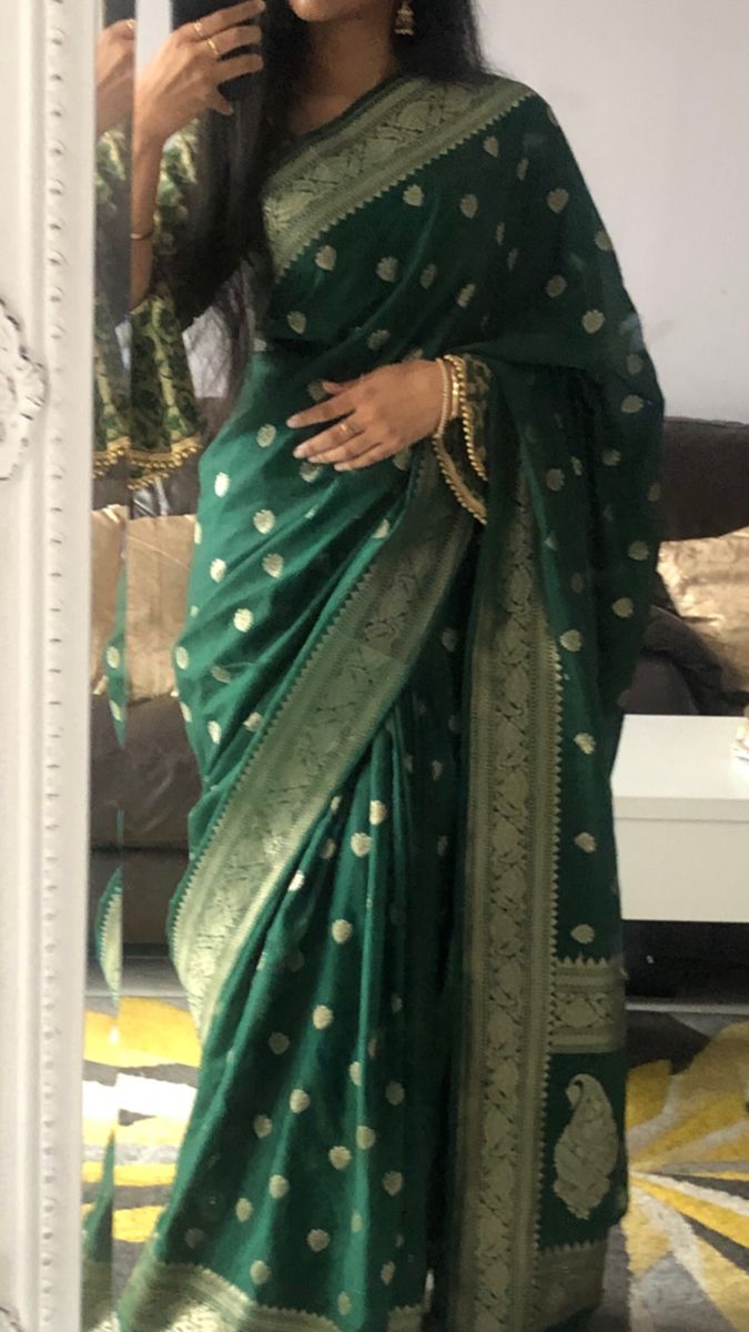 a woman in a green and gold sari is taking a selfie with her cell phone