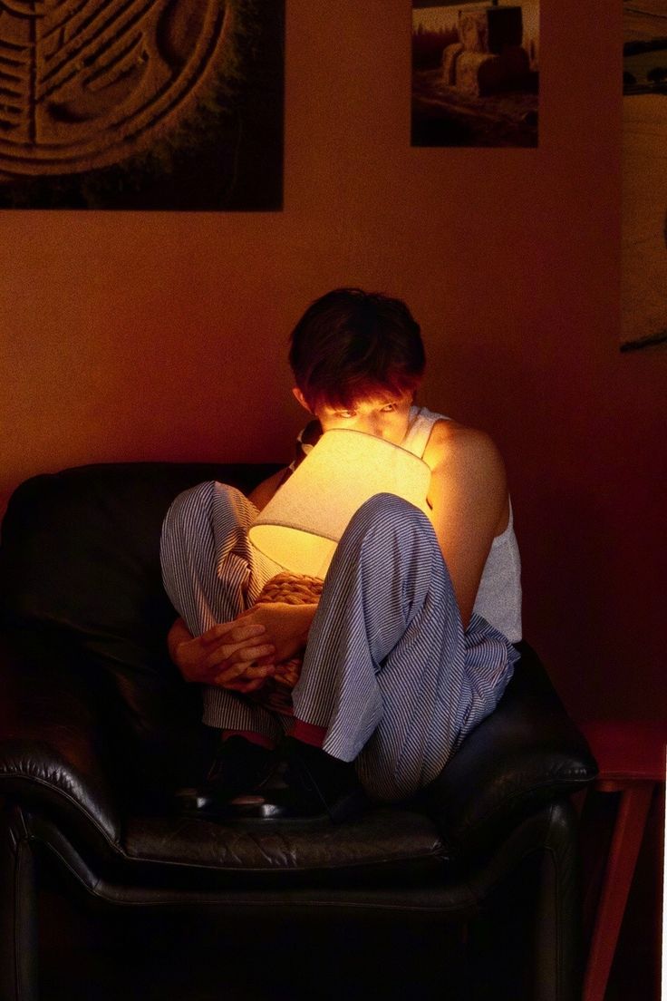 a woman sitting in a chair reading a book with a lamp on her arm and legs