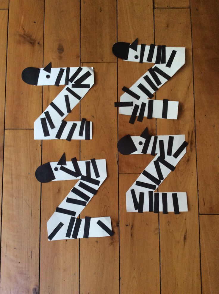 four zebras made out of strips of paper on a wooden floor with black and white stripes