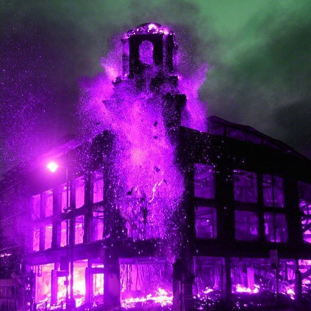 the building is lit up with purple lights and water spewing out of it