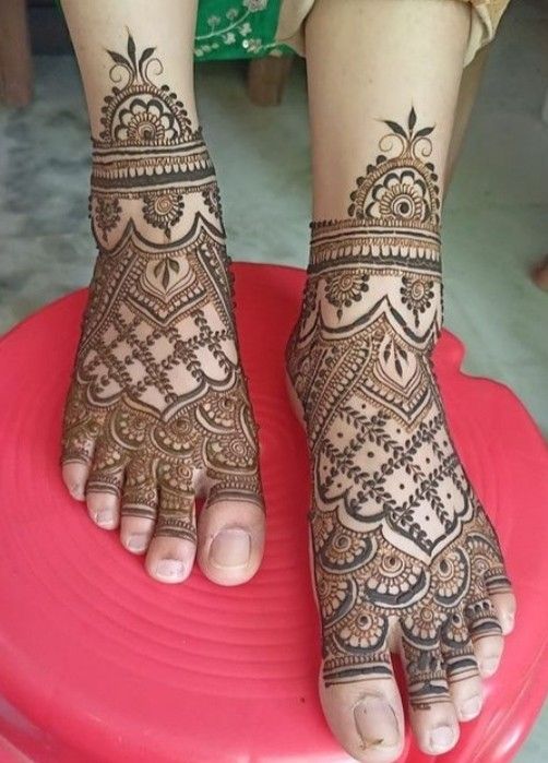 the feet are decorated with henna on top of a red object in front of a woman's legs