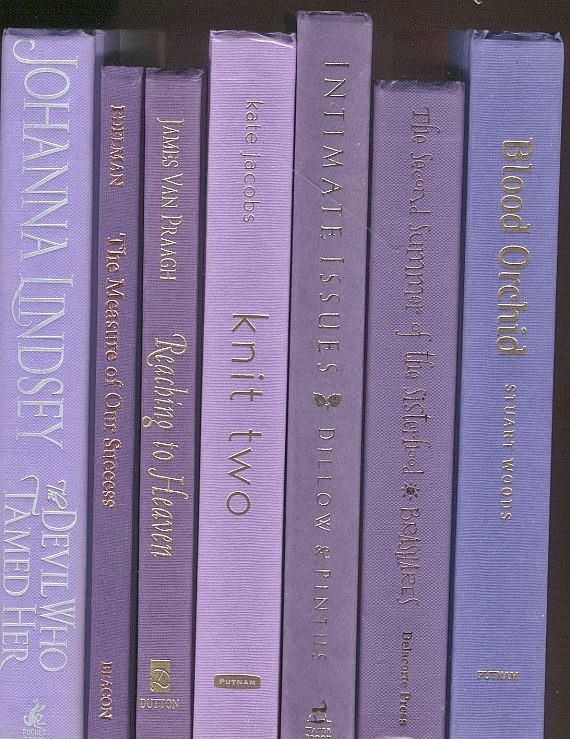 a row of purple books sitting on top of a shelf