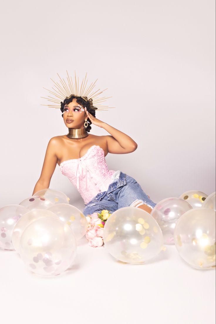 a woman sitting on the ground surrounded by balloons