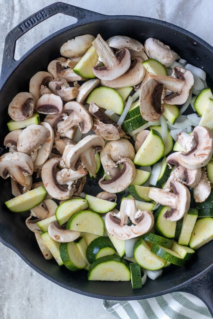 mushrooms, zucchini and cucumbers in a skillet on a table