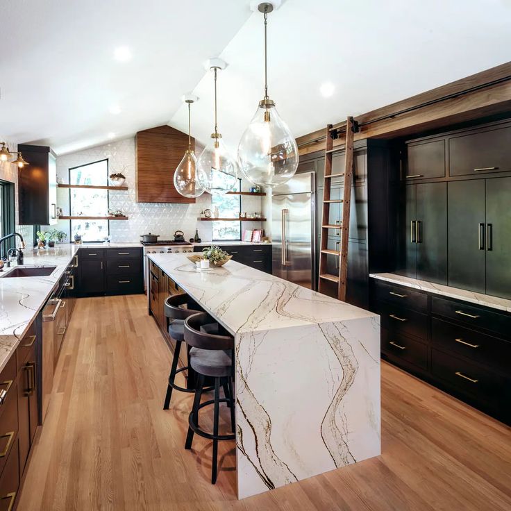 a large kitchen with marble counter tops and wooden flooring, along with black cabinets