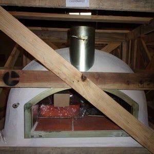 an oven is built into the side of a building with wooden beams and brick flooring