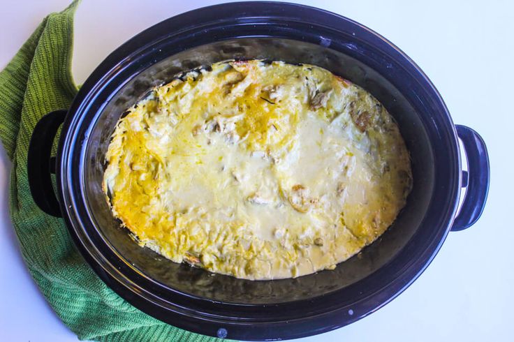 an oval casserole in a black crock pot with a green napkin next to it