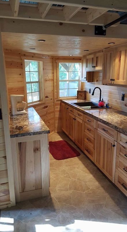 a kitchen with wooden cabinets and granite counter tops in a log cabin style home setting