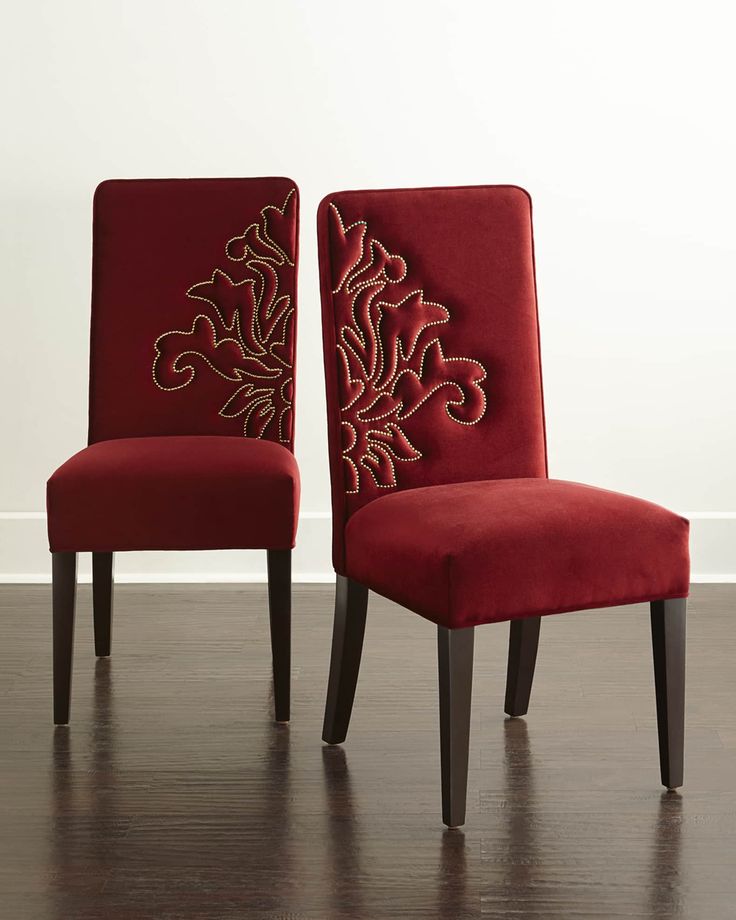 two red chairs sitting on top of a hard wood floor next to a white wall