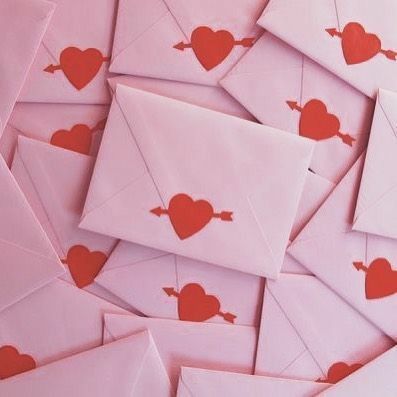 pink envelopes with red hearts on them are piled together in a pile to be used as valentine's day cards