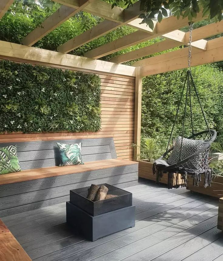 an outdoor living area with wood flooring and plants on the wall, hanging from a pergolated roof