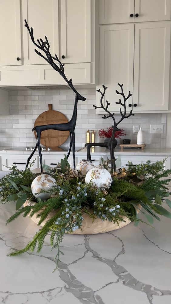 a kitchen with white cabinets and countertops decorated for christmas, including an antelope centerpiece