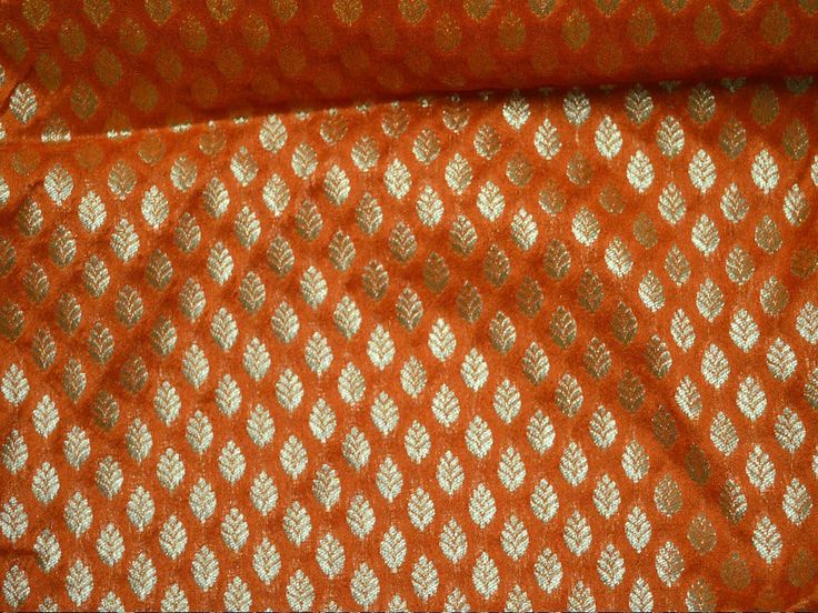 an orange and white fabric with gold leaf designs on the side, in close up