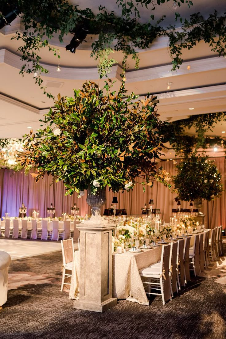 an elegant table set up with white linens and greenery for a wedding reception