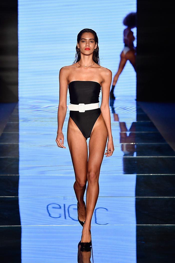 a model walks down the runway in a black and white one - piece swimsuit