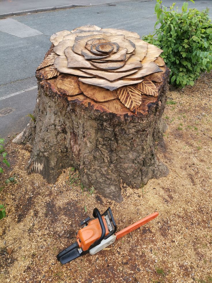 an orange and black chainsaw sitting on the ground next to a tree stump