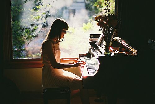 a woman sitting at a piano in front of a window