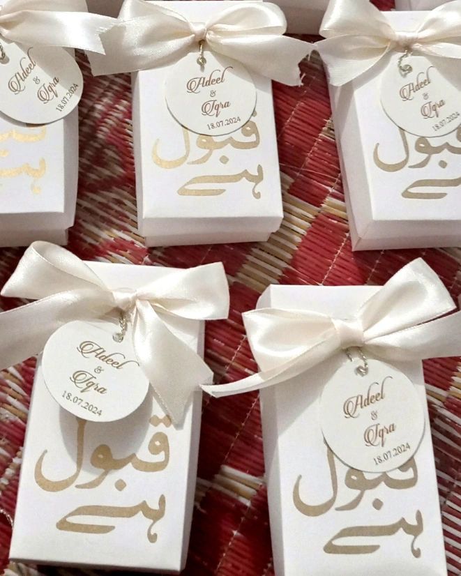 four white boxes with bows and tags on them sitting on a plaid tablecloth covered table