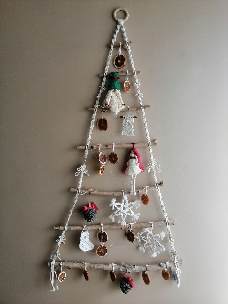 a crocheted christmas tree is hanging on the wall with other ornaments around it