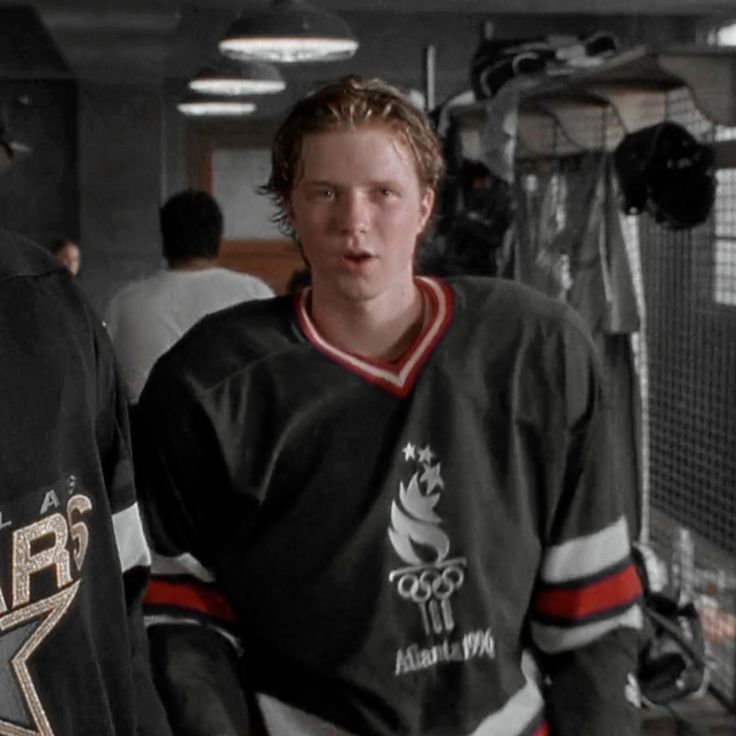 two young men standing next to each other in front of an ice hockey goalie