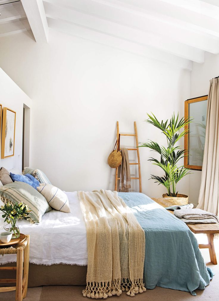 a bedroom with a bed, chair and potted plant on the side table in front of it