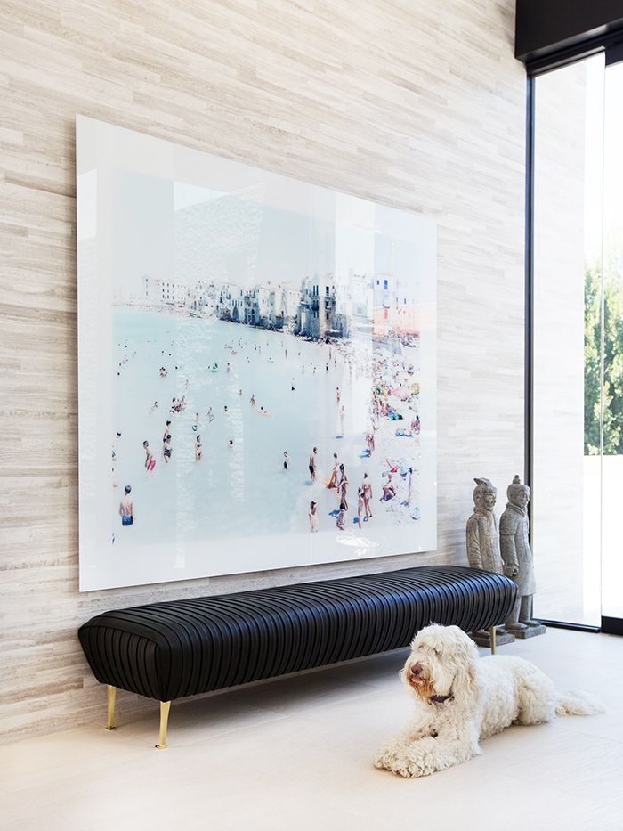 a white dog laying on the floor in front of a large art piece and painting