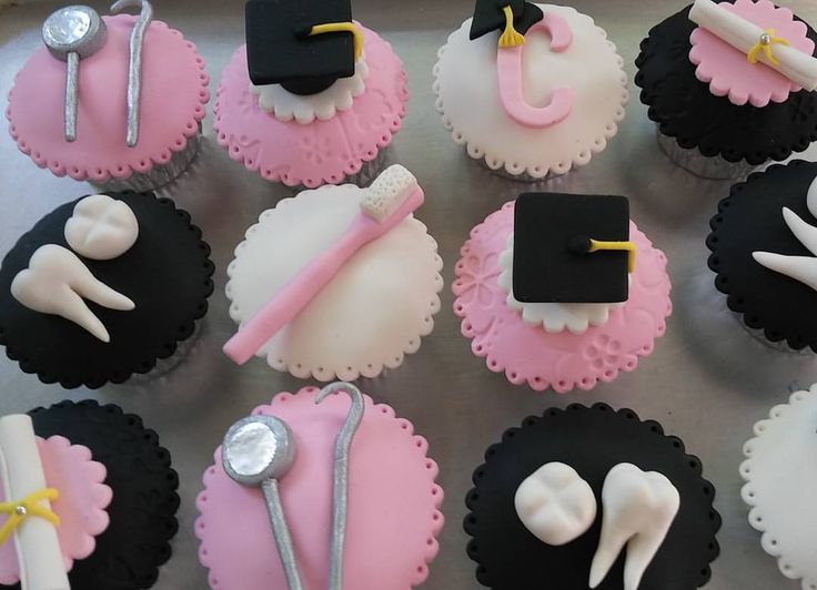 cupcakes decorated with fondant and icing are arranged on a tray in the shape of graduation caps