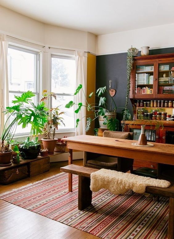 a living room filled with lots of furniture and plants on top of a wooden table