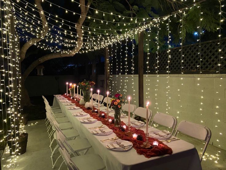 a long table is set with candles and place settings for an outdoor dinner or party