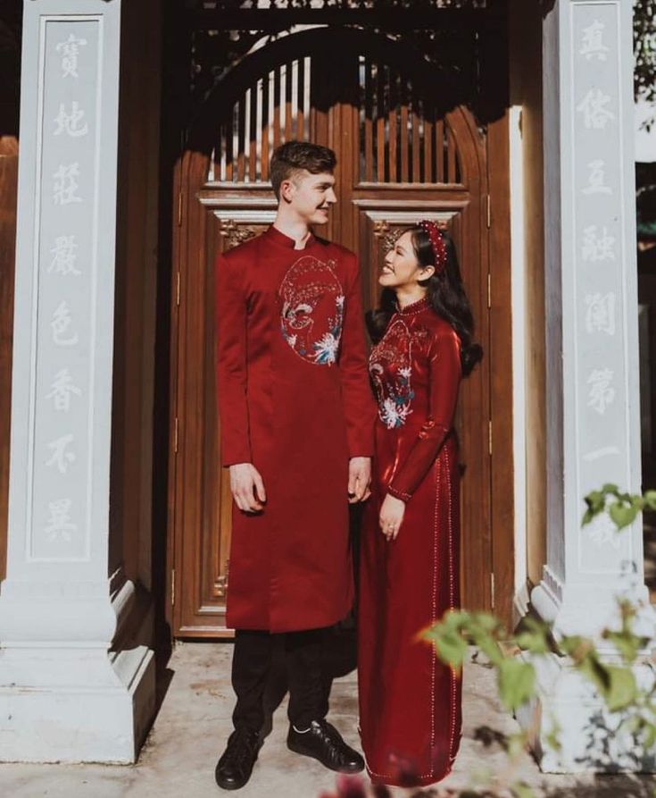 a man and woman standing in front of a building with chinese writing on the doors