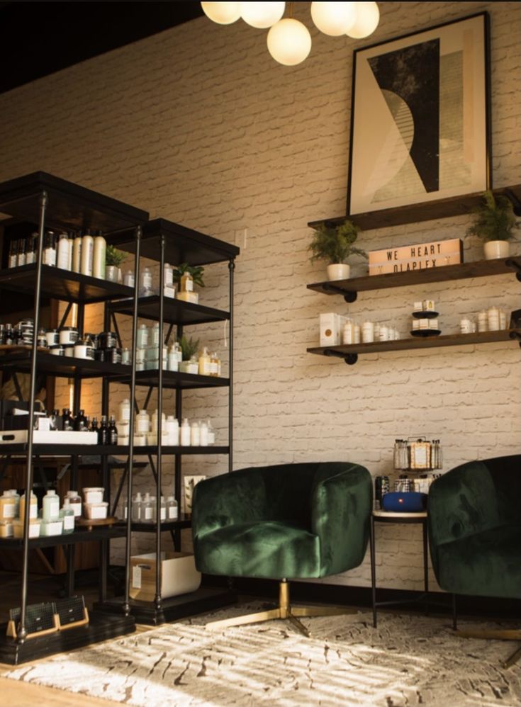 two green chairs sitting next to each other in front of shelves with candles on them