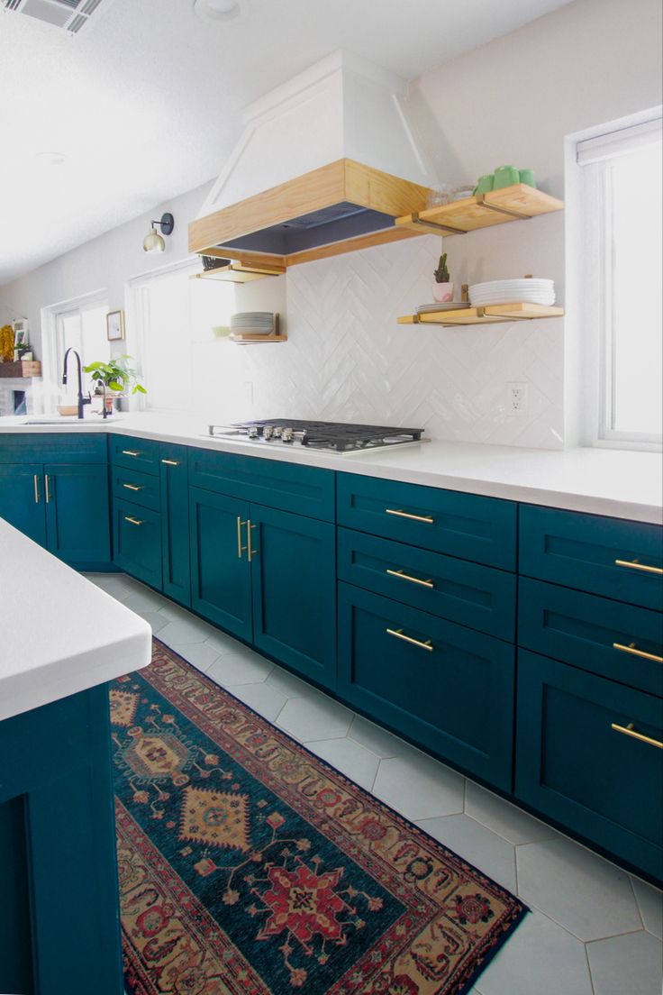 a kitchen with teal cabinets and white counter tops, rug on the floor in front of it