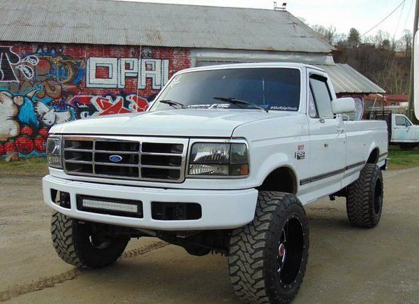 a large white truck parked in front of a graffiti covered building with black tires on it