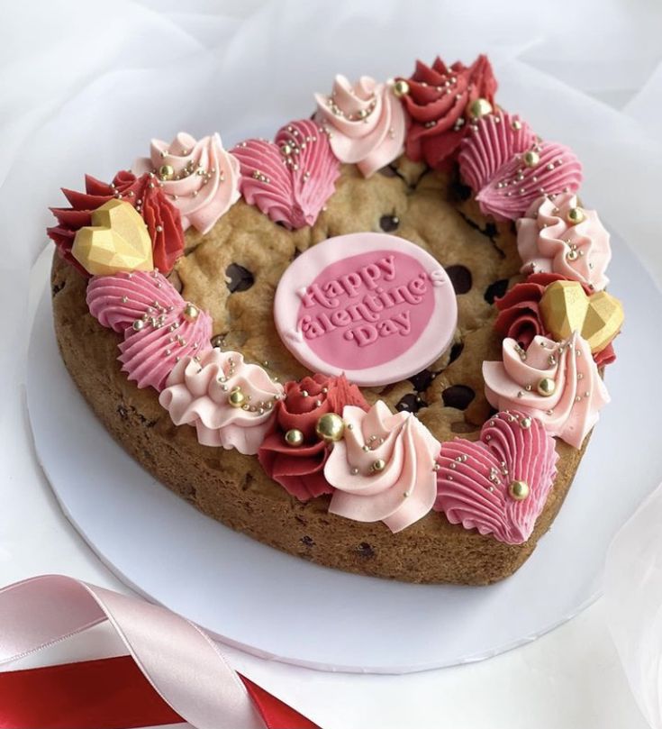 a heart shaped cookie decorated with pink frosting and gold decorations on a white plate