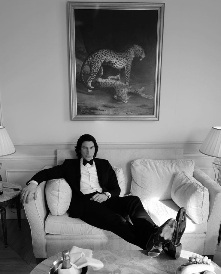 a man in a tuxedo sitting on a couch with his feet propped up