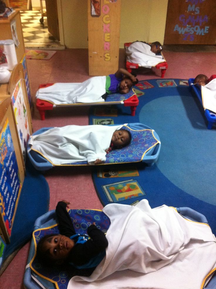 there are many children sleeping on their beds in the floored area at the library