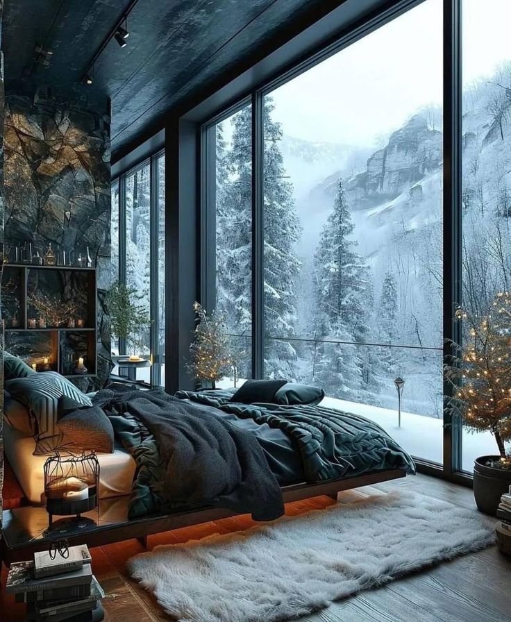 a bedroom with a large window overlooking the mountains and snow covered trees is shown in this image