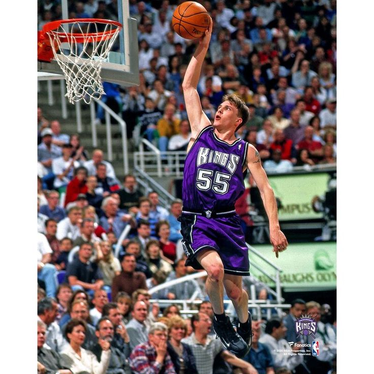 a basketball player jumping up to dunk the ball in front of an arena full of people