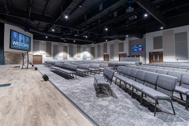 an empty auditorium with rows of chairs and a flat screen tv on the wall above it