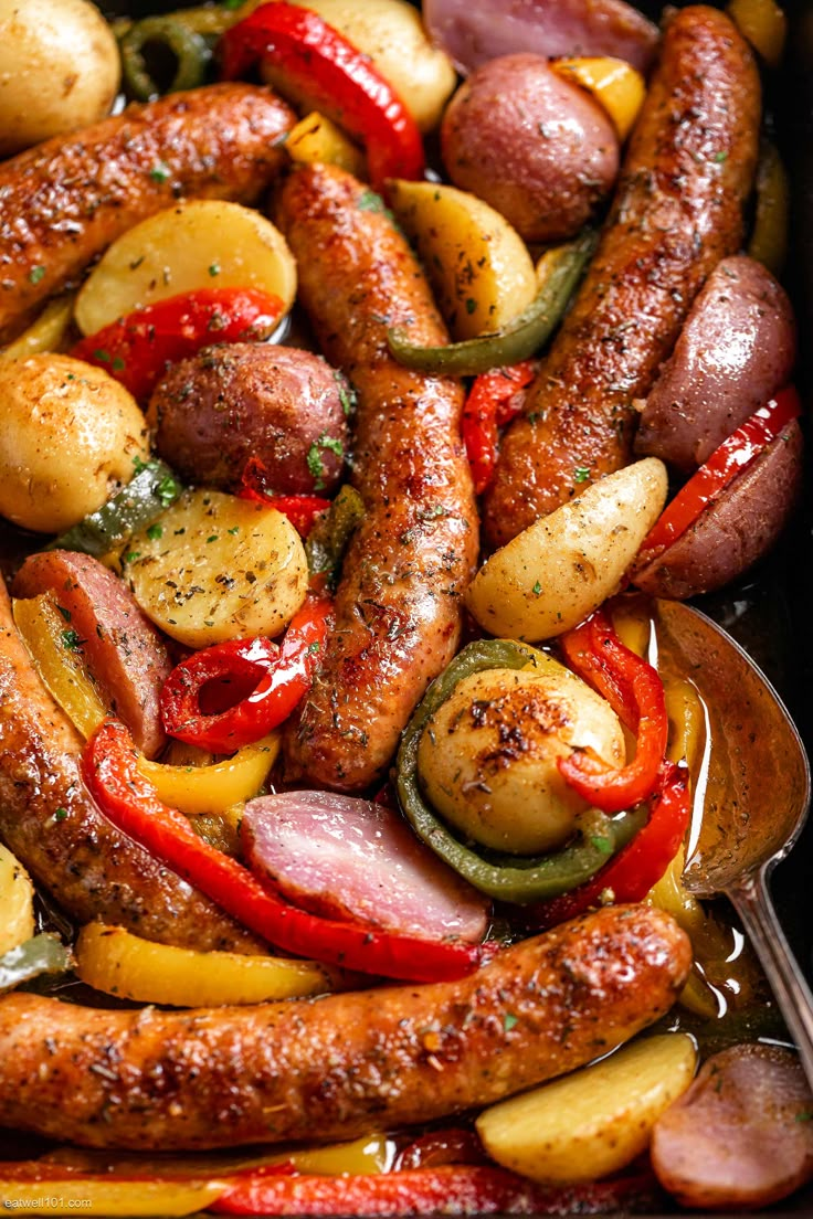 sausages, potatoes and peppers in a pan with a serving spoon on the side