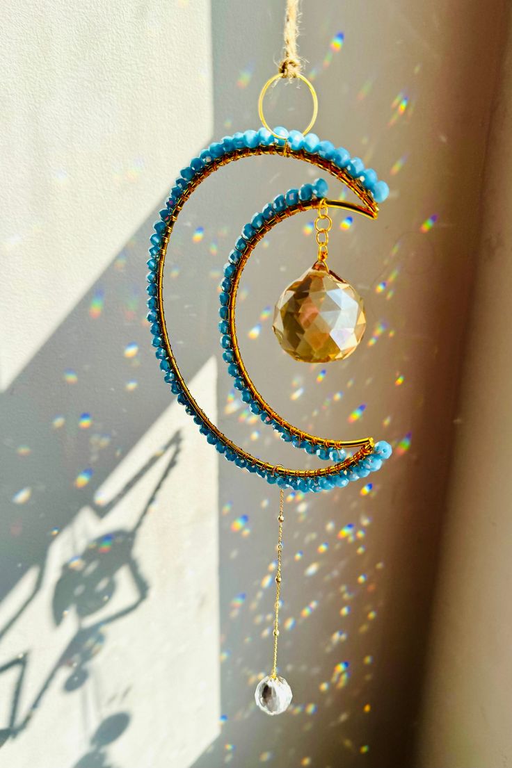 a wind chime hanging from the side of a wall with beads and crystals on it