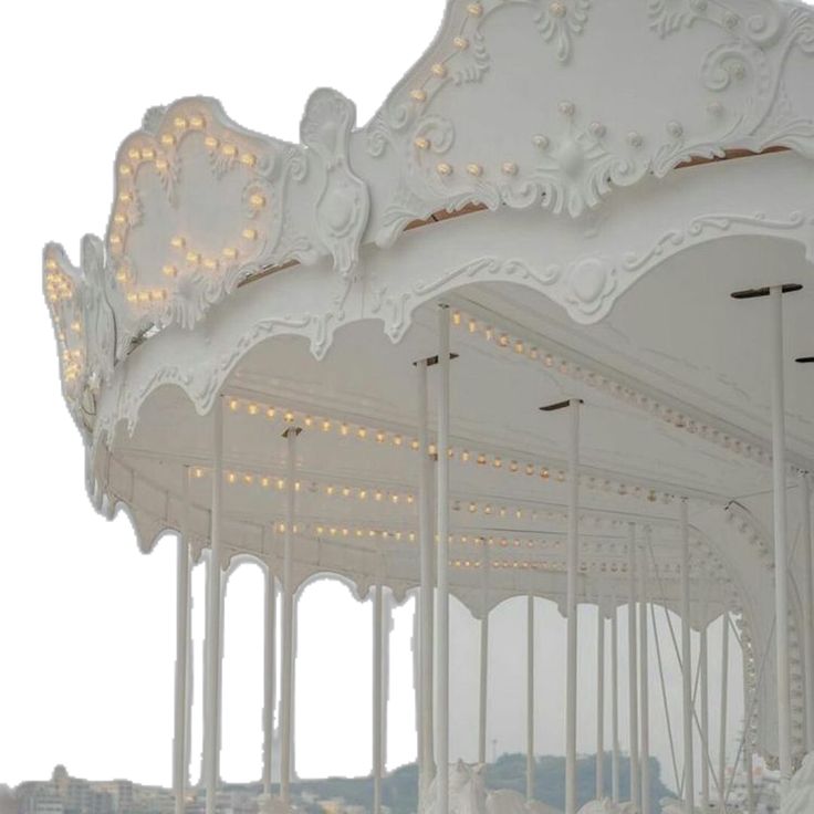 an ornately decorated white carousel with lights on it's sides and the roof